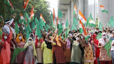 Women farmers hold the national flag during their protest ahead of UP chief minister Yogi Adityanath's visit outside Greater Noida authority, Tuesday. (PTI)