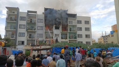 Bystanders watch firemen trying to put off the flames and bring the situation under control outside the apartment at Devarachikkana Halli area in Bengaluru. (ANI Photo).