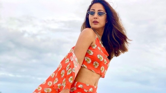 The pictures featured the actor donning an orange base draped neck crop top that came with noodle straps and sported white sunflower motifs printed all over.(Instagram/realhinakhan)