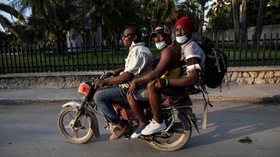 Pierre Charles (C), a Haitian deported from the US shares a motorcycle taxi with a fellow deportee, after leaving the Toussaint Louverture International Airport, in Port au Prince, Haiti, on September 20. Many Haitians have established at least temporary legal status in Mexico, Brazil and elsewhere. Some have spouses or children from their adopted countries.(Rodrigo Abd / AP)