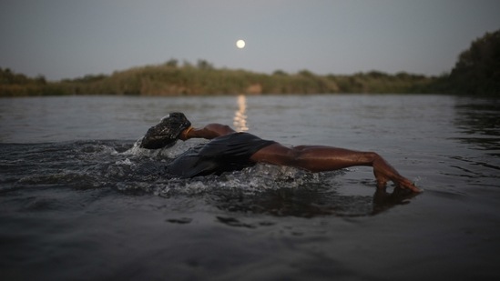 A Haitian migrant swims across the Rio Grande river from Del Rio, Texas, to Ciudad Acuña, Mexico, late on September 19 to avoid deportation to Haiti from the US.&nbsp;(Felix Marquez / AP)