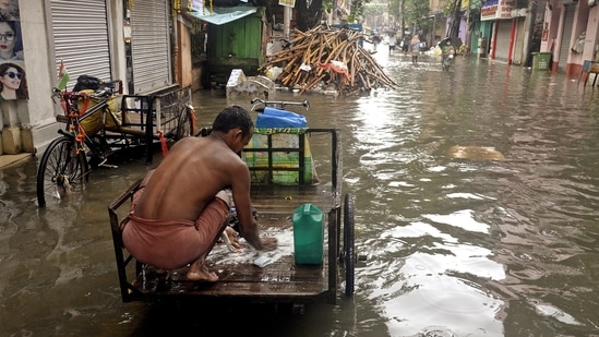 A man washes his clothes on his rickshaw in the waterlogged road following heavy rainfall in Kolkata.(ANI)
