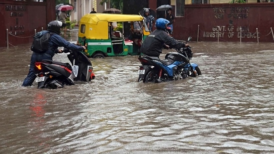 Commuters pull their vehicles through a waterlogged road after heavy rainfall, in Kolkata.(ANI)