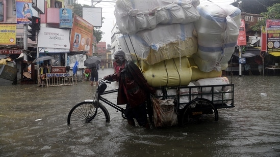 A labour pulls a cart loaded with goods on a waterlogged road following heavy rainfall in Kolkata.(ANI)