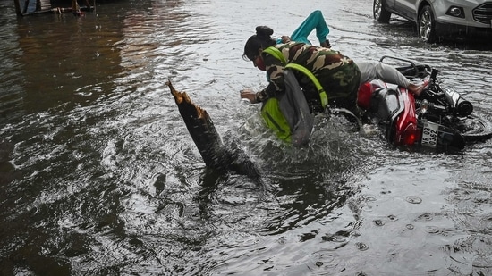 A motorcyclist and the pillion stumble while crossing a waterlogged street after heavy rainfall in Kolkata.(AFP)