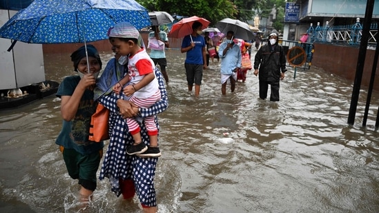 People carrying umbrellas cross a waterlogged street after heavy rainfall in Kolkata on September 20, 2021 reportedly triggered by cyclonic circulation formed over the Bay of Bengal.&nbsp;(AFP)