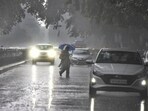 A person crosses the road during rain at Janpath on Tuesday.(Raj K Raj/HT Photo)