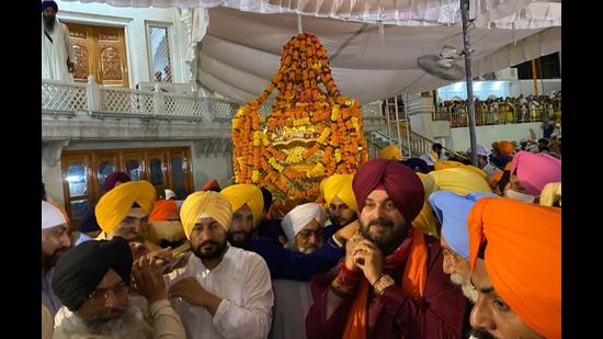 Punjab chief minister Charanjit Singh Channi (left) and state Congress president Navjot Singh Sidhu carrying the Palki Sahib at the Golden Temple in Amritsar early on Wednesday. (Sameer Sehgal/HT)