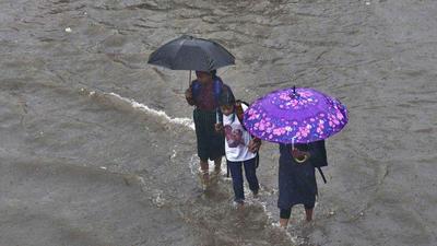 Pedestrians walk through a waterlogged road in Ludhiana after downpour on Thursday. Normally, withdrawal starts from mid-September but this time, heavy showers are being witnessed even in the penultimate week of the month. (Gurpreet Singh/HT)
