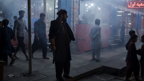 A Taliban fighter stands in the corner of a busy street at night in Kabul. A Taliban fighter stands in the corner of a busy street at night in Kabul.
