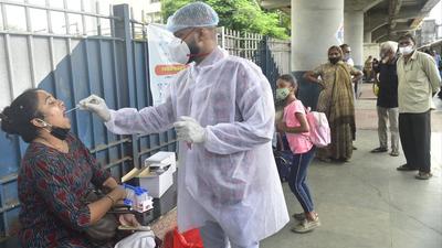A BMC health worker collects swab samples for Covid-19 test of passengers arriving on outstation trains at Dadar station, in Mumbai. (Anshuman Poyrekar/HT PHOTO)