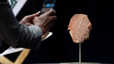 A man photographs the Gilgamesh Tablet, a 3,500-year-old Mesopotamian cuneiform clay tablet that was believed to be looted from Iraq around 1991 and illegally imported into the US to be displayed at the Washington Museum of the Bible, during a ceremony to repatriate the tablet to Iraq, at the Smithsonian National Museum of the American Indian, in Washington, DC, (Photo by SAUL LOEB / AFP) A man photographs the Gilgamesh Tablet, a 3,500-year-old Mesopotamian cuneiform clay tablet that was believed to be looted from Iraq around 1991 and illegally imported into the US to be displayed at the Washington Museum of the Bible, during a ceremony to repatriate the tablet to Iraq, at the Smithsonian National Museum of the American Indian, in Washington, DC, (Photo by SAUL LOEB / AFP)