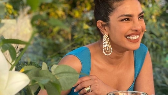 The first picture featured her sitting at a brunch table, donning a radiant blue dress that came with broad straps and a sweetheart neckline. Pulling back her silky tresses into a top knot, Priyanka flaunted a pair of dangling earrings and accessorised her look further with a silver ring as she opted for dewy makeup and flashed her million dollar smile for a candid picture.(Instagram/priyankachopra)