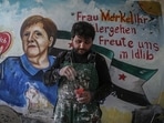 Amsar in front of the mural of Angela Merkel that he painted in March 2020