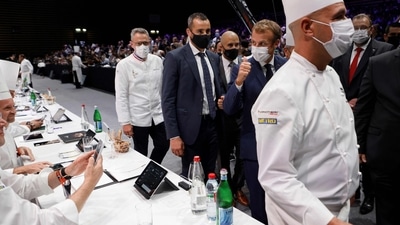French President Emmanuel Macron salutes jury members of the Bocuse d'Or gastronomy contest during a food trade fair. (AFP)