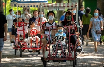 dults and children ride pedal cycles at a public park in Beijing (PTI Photo) dults and children ride pedal cycles at a public park in Beijing (PTI Photo)