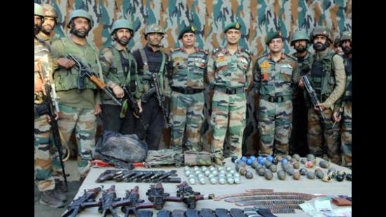 Indian Army personnel displaying arms and ammunitions recovered from three militants killed in Uri area of Baramulla district on September 23. (PTI Photo)
