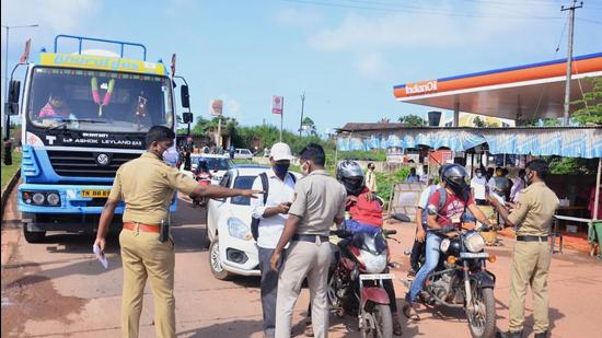 Police personnel check the Covid-19 test report of travellers at Talapady checkpost at Kerala-Karnataka border in Mangaluru. (PTI)