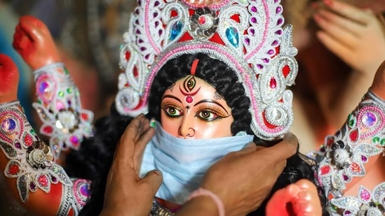 A devotee puts a mask on the face of a Goddess Durga idol to aware people against Covid-19. (PTI Photo) A devotee puts a mask on the face of a Goddess Durga idol to aware people against Covid-19. (PTI Photo)