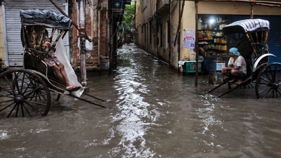 Hand-pulled rickshaw drivers on a waterlogged road after overnight rains, in Kolkata. (PTI Photo)
