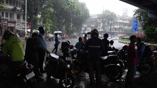 Commuters take shelter under a bridge amid heavy rainfall, in Mumbai on Tuesday. (ANI Photo)