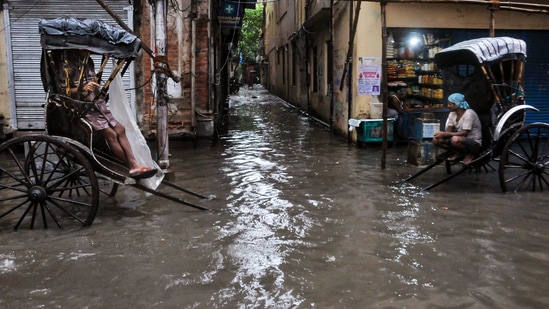 Hand-pulled rickshaw drivers on a waterlogged road after overnight rains, in Kolkata.(PTI Photo)