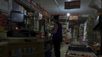 A woman buys groceries from a mini market using a light bulb powered by gasoline generator during a blackout in Shenyang in northeastern China’s Liaoning Province. Provinces and regions including Liaoning and Jilin in northeast China, the trading powerhouse Guangdong in the south and Zhejiang in the east have been in the grip of power shortage for weeks now. (AP)