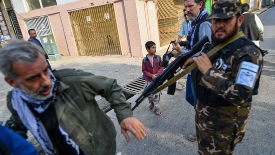 A member of the Taliban special forces pushes a journalist (L) covering a demonstration by women protestors outside a school in Kabul on September 30, 2021. (Photo by BULENT KILIC)(AFP) A member of the Taliban special forces pushes a journalist (L) covering a demonstration by women protestors outside a school in Kabul on September 30, 2021. (Photo by BULENT KILIC)(AFP)