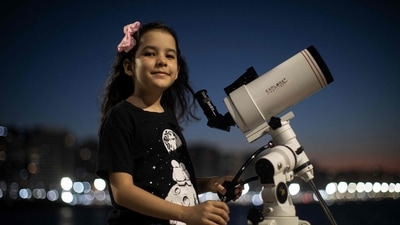 Brazilian 8-year-old astronomer Nicole Oliveira poses for a picture with her telescope in Fortaleza, Brazil. (AFP)