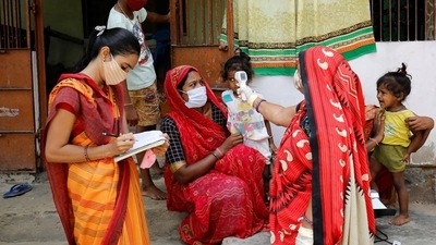 A healthcare worker checks the temperature of a child during a door-to-door surveillance to safeguard children amidst the spread of the coronavirus disease at a village on the outskirts of Ahmedabad.&nbsp; (File photo / Reuters)