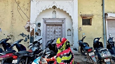 The door is painted white. The wooden strips on either sides are carved with three separate designs, running from top to bottom. The door is painted white. The wooden strips on either sides are carved with three separate designs, running from top to bottom.