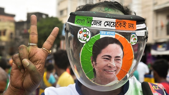 A Trinamool Congress supporter flashes victory sign wearing a face shield with a photo of party supremo and West Bengal chief minister Mamata Banerjee outside her residence in Kolkata's Kalighat, on Sunday.&nbsp;(PTI)