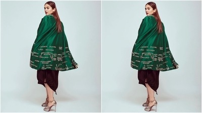 Huma's look for the photoshoot features a black spaghetti-strapped slip dress with a flowy silhouette and an asymmetric hem with tie detail on one corner. She paired the classic black ensemble with a notch lapel silk cape jacket adorned with slits to pull the arms out and hymns printed in white shade. (Instagram/@iamhumaq)