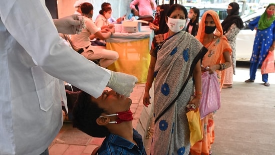 A health worker takes a swab sample from a youth to test for the Covid-19 coronavirus at a testing center in New Delhi. ( AFP)