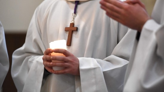 In this file photo taken on March 27, 2021, an altar boy holds a candle during a mass in Brest, western France. (Photo by Fred TANNEAU)(AFP) In this file photo taken on March 27, 2021, an altar boy holds a candle during a mass in Brest, western France. (Photo by Fred TANNEAU)(AFP)