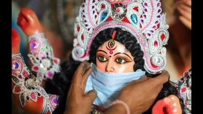 A devotee puts a mask on the face of a Goddess Durga idol to make aware people about the Covid-19 pandemic protocol at a community puja pandal. (PTI file photo) A devotee puts a mask on the face of a Goddess Durga idol to make aware people about the Covid-19 pandemic protocol at a community puja pandal. (PTI file photo)