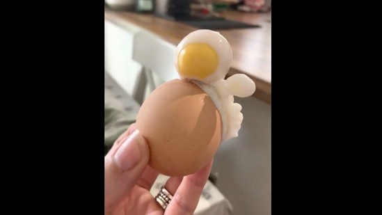 This is a still from the video showing a woman holding a boiled egg in her hand. Screengrab