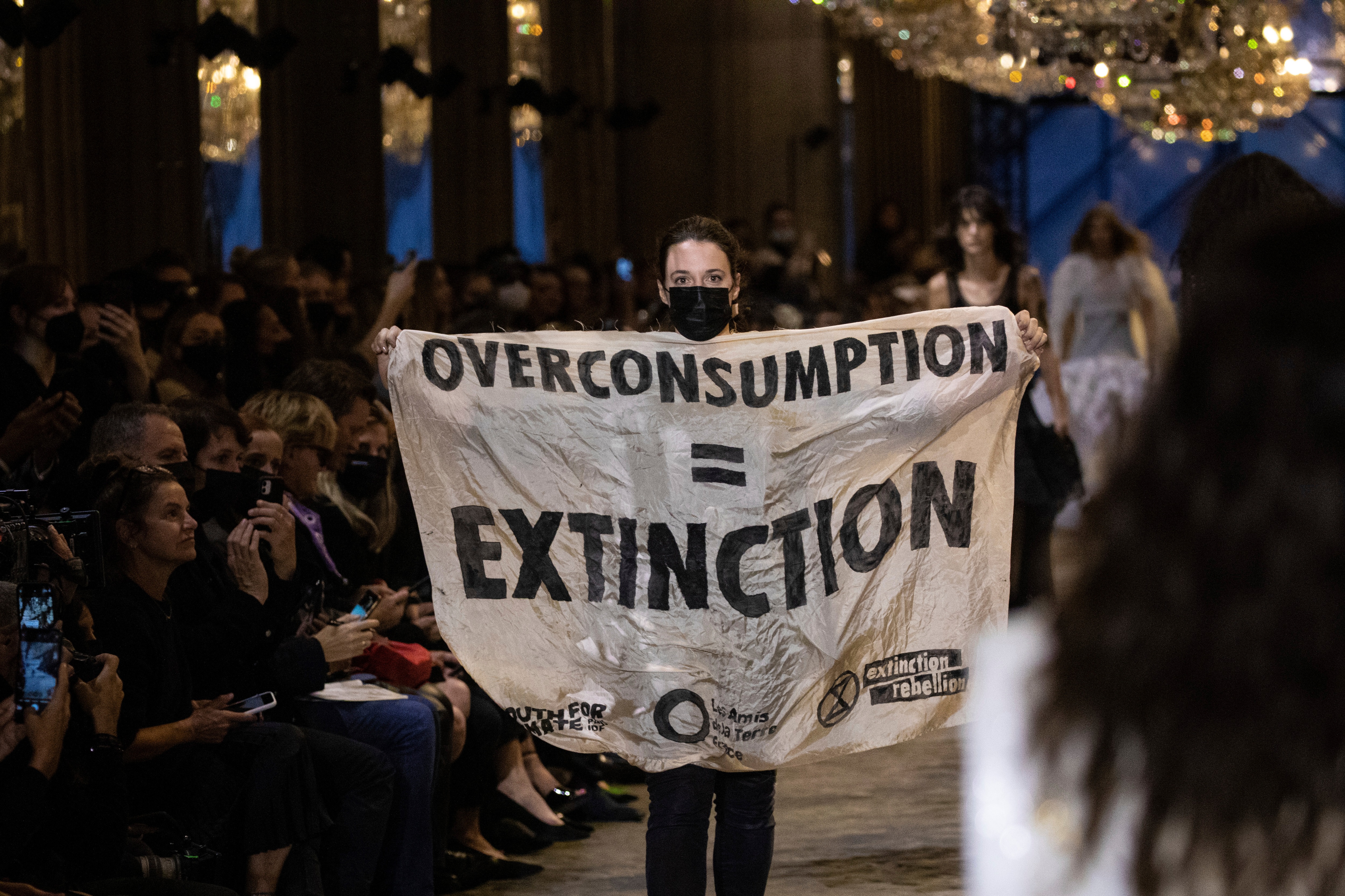 A protestor holds a banner on the runway during the Louis Vuitton Spring-Summer 2022 ready-to-wear fashion show (Vianney Le Caer/Invision/AP) A protestor holds a banner on the runway during the Louis Vuitton Spring-Summer 2022 ready-to-wear fashion show (Vianney Le Caer/Invision/AP)
