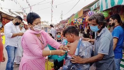 A medic administers a dose of Covid-19 vaccine to shopkeepers outside a Goddess Kali temple during a special vaccination drive, in Jammu, on Tuesday. (PTI) A medic administers a dose of Covid-19 vaccine to shopkeepers outside a Goddess Kali temple during a special vaccination drive, in Jammu, on Tuesday. (PTI)