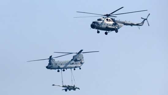 An Indian Air Force (IAF) Chinook helicopter carries an artillery gun alongside a MI-17 helicopter during the Air Force Day Parade at Hindon Air Force Station in Ghaziabad.(Bloomberg)