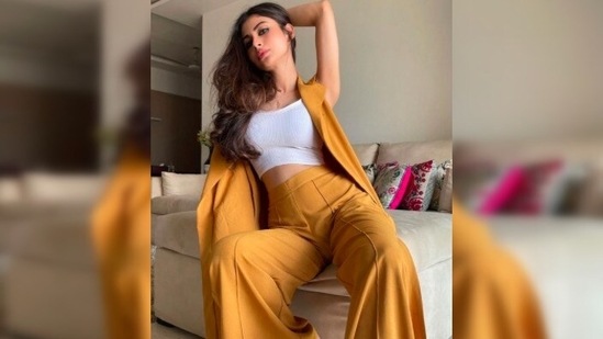 Mouni Roy donned mustard yellow high-rise trousers which she teamed with a white crop top and a sleeveless yellow cape.(Instagram/@imouniroy)
