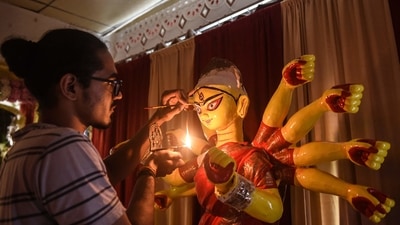 An artist in Ahmedabad holds a diya in his right hand and paints Goddess Durga's eyes with his left hand ahead of the main celebrations of Durga Puja. (AFP) An artist in Ahmedabad holds a diya in his right hand and paints Goddess Durga's eyes with his left hand ahead of the main celebrations of Durga Puja. (AFP)