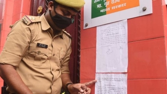 At Union minister Ajay Mishra’s house, a police officer on Friday pastes a second notice to summon son Ashish Mishra for questioning as a witness in the Lakhimpur Kheri case.&nbsp;(HT Photo)