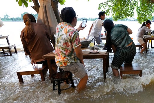 Customers of the riverside Chaopraya Antique Café react to a boat's wake (AP) Customers of the riverside Chaopraya Antique Café react to a boat's wake (AP)