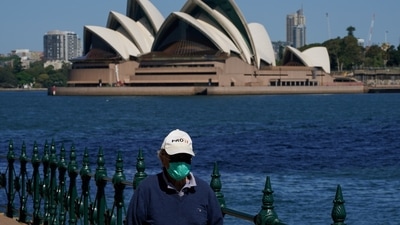FILE PHOTO: A person walks along the harbour waterfront across from the Sydney Opera House during a lockdown.&nbsp; (REUTERS/Loren Elliott/File Photo)
