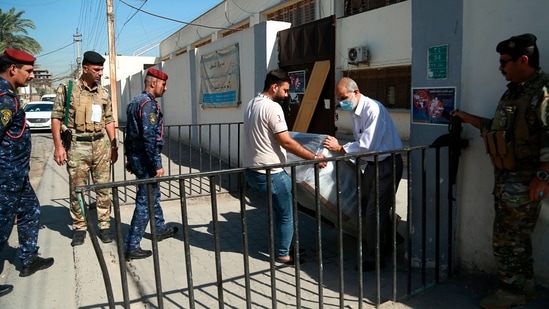 Workers from Iraq's electoral commission unload voting equipment while security forces stand guard at a polling station in Baghdad, Iraq, Thursday, Oct. 7, 2021.(AP) Workers from Iraq's electoral commission unload voting equipment while security forces stand guard at a polling station in Baghdad, Iraq, Thursday, Oct. 7, 2021.(AP)