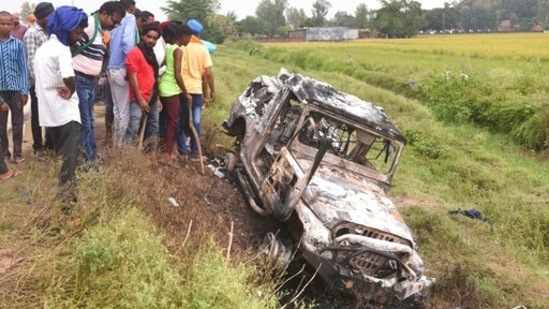 Villagers watch a burnt car which ran over and killed farmers on Sunday, at Tikonia village in Lakhimpur Kheri, Uttar Pradesh.(AP)
