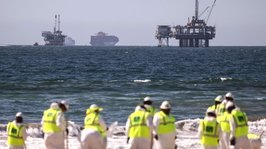 Cleanup workers search for contaminated sand and seaweed in front of drilling platforms and container ships about one week after an oil spill from an offshore oil platform. The heavy crude oil spill affected close to 25 miles of coastline in Orange County. Huntington Beach is open but the public is not allowed to enter the water.&nbsp;(Mario Tama/Getty Images/AFP)