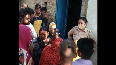 A woman cop and locals at the crime scene in trans-Yamuna region of Prayagraj. (HT)
