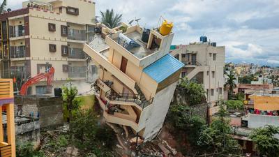 BBMP demolish a building after it developed cracks following heavy rains at Kamlanagar, in Bengaluru, Wednesday. (PTI)